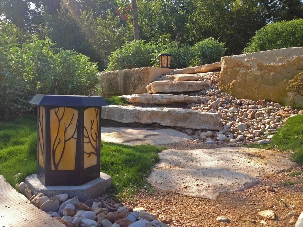 Stone steps leading up a hill with a decorative lamp in a garden setting.