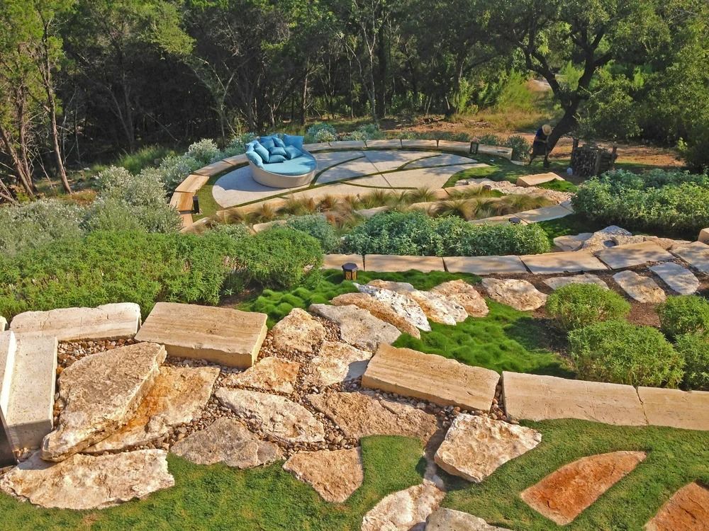 Stone path and seating area with blue cushioned furniture surrounded by plants.