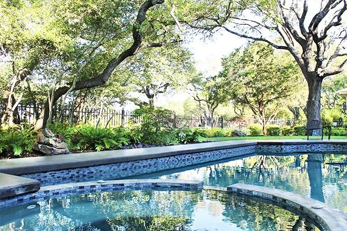 Swimming pool with turquoise water, surrounded by trees and lush greenery.