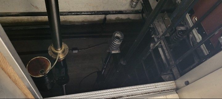 Open ceiling space with exposed pipes, ducts, and wiring above a stairwell