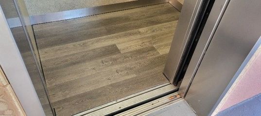 Open elevator doorway with wood-look floor and metal threshold