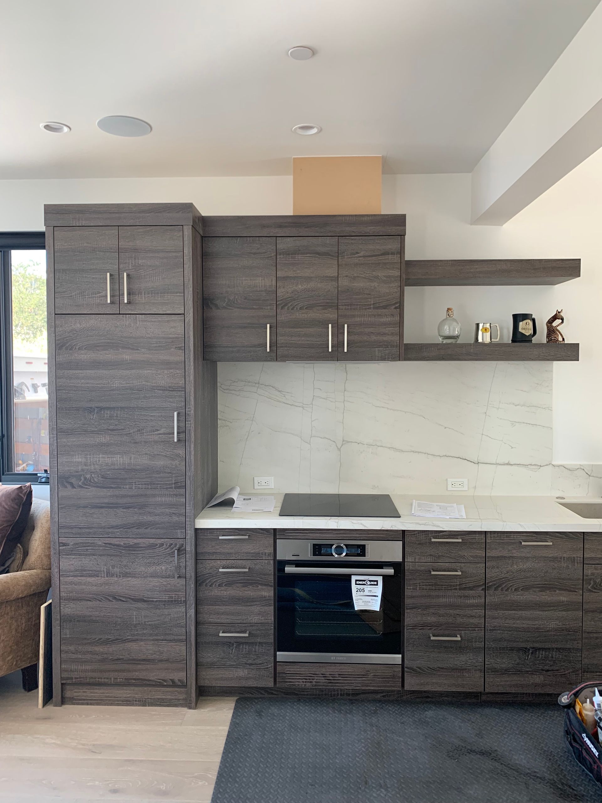 Modern kitchen with gray cabinets, white countertops, and built-in oven under open shelving