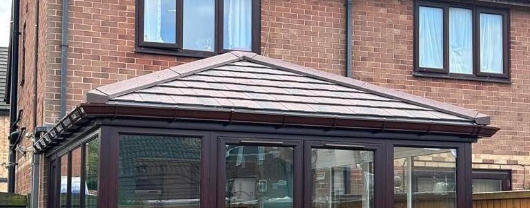 A white house with green windows and a black roof.