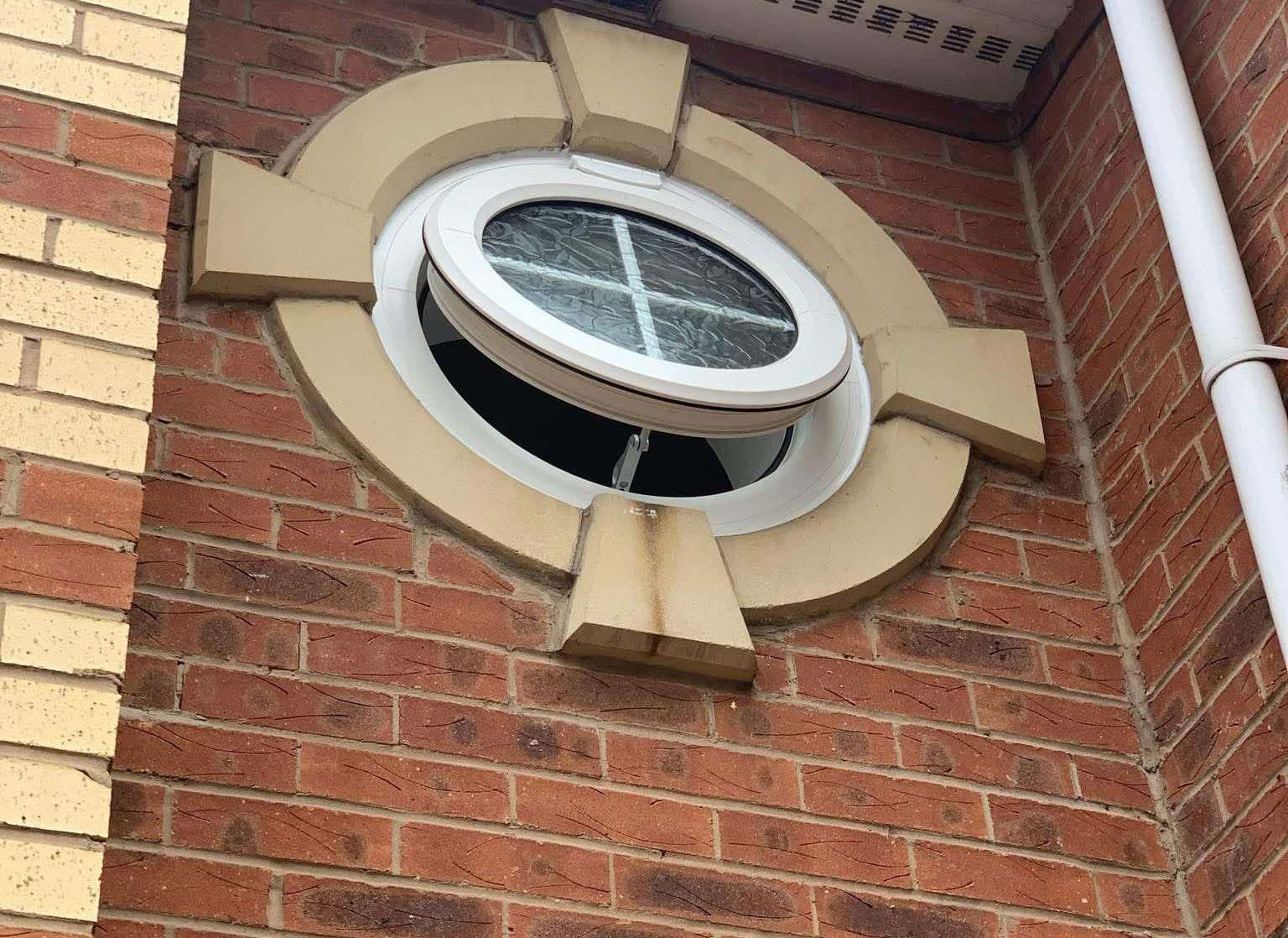A large window on a stone wall surrounded by flowers