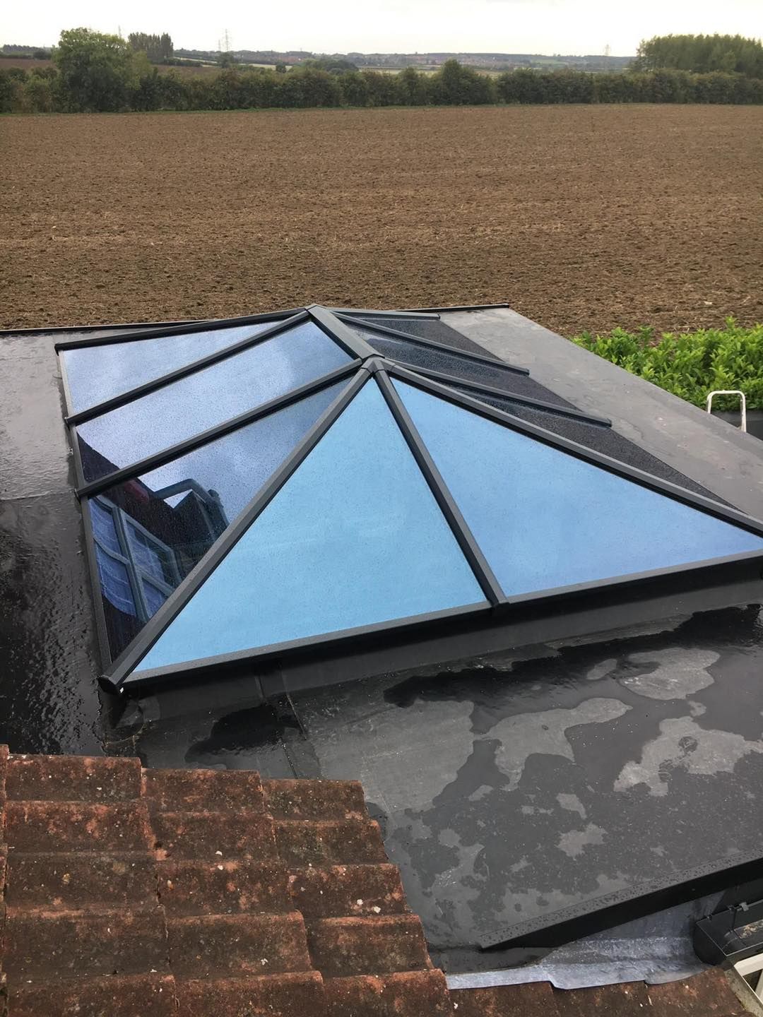A skylight on top of a roof with a field in the background.