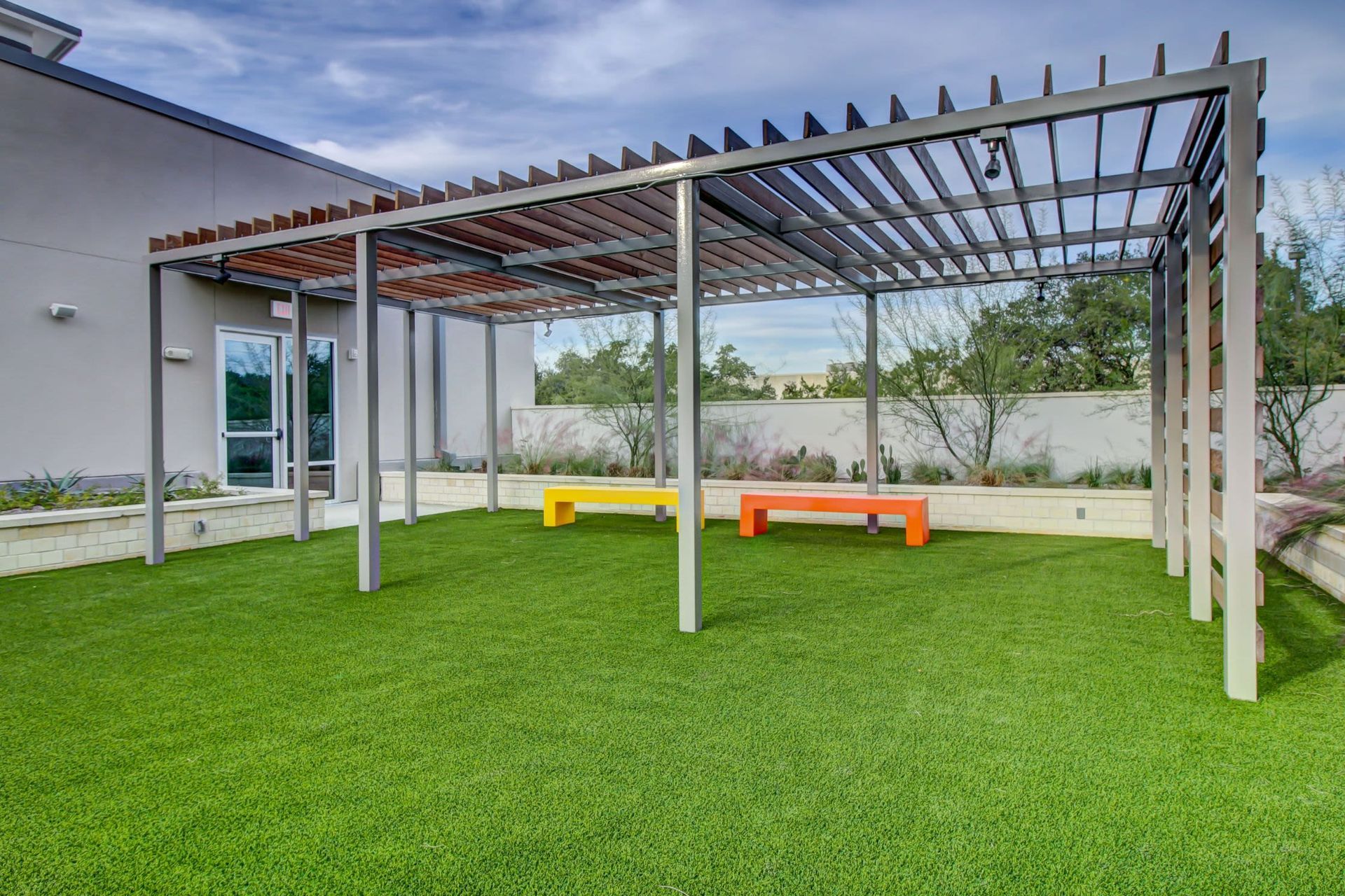 a pergola with benches underneath it is sitting on top of a lush green lawn at Westerly 360 in Austin, TX.