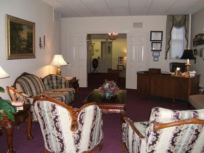 An artist 's impression of a hotel lobby with a couch , chairs , and plants.