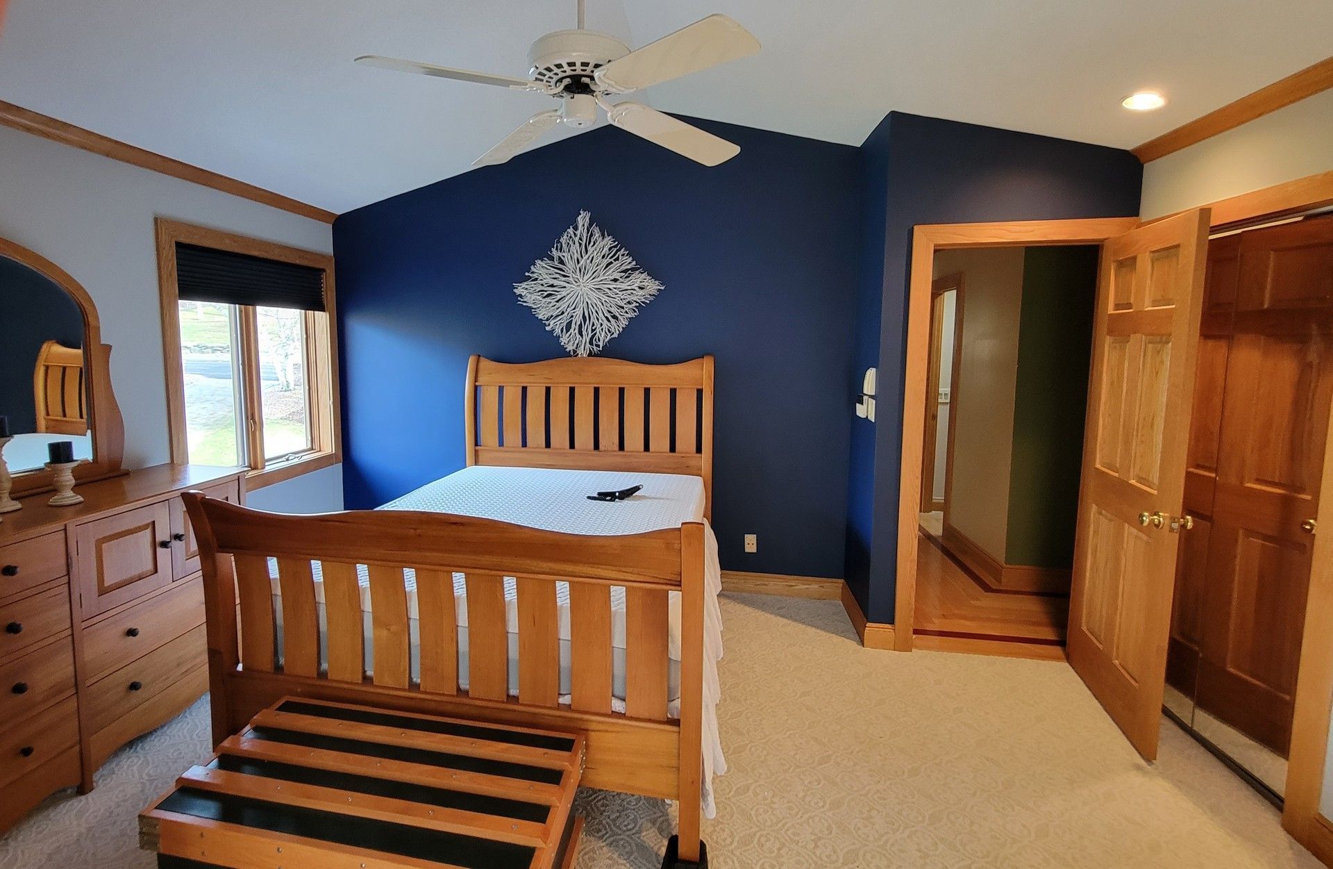 A bedroom with a bed , dresser , mirror and ceiling fan.