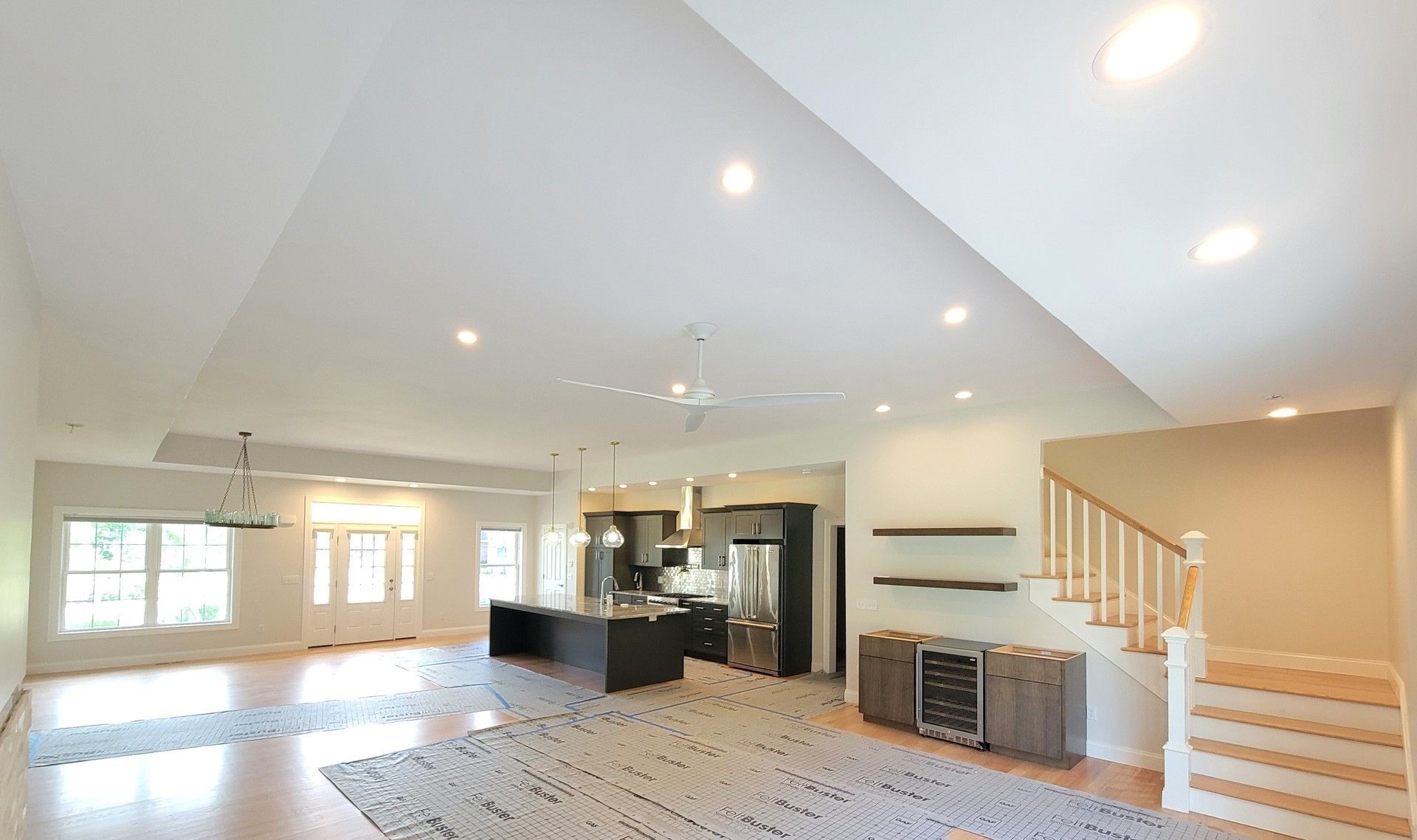 A large empty room with a ceiling fan and stairs