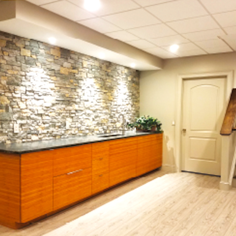A kitchen with a stone wall and wooden cabinets