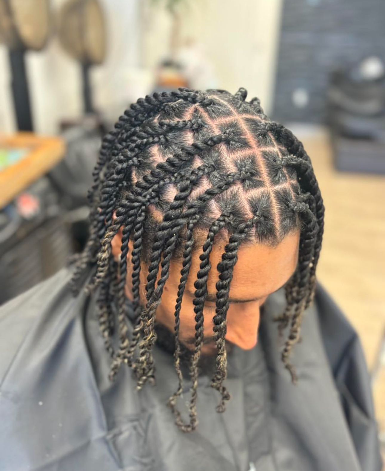 A woman with braids in a ponytail is sitting in a chair.