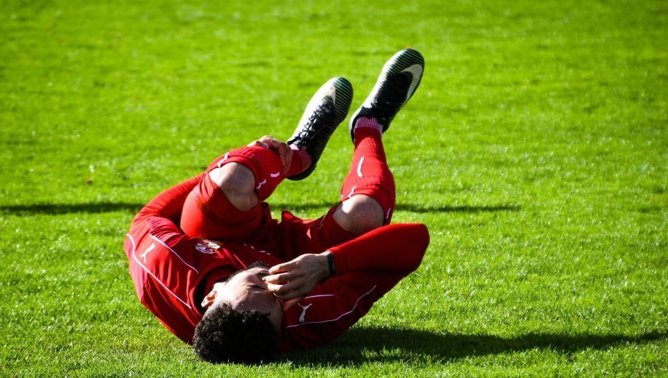 A soccer player is laying on the ground with a knee injury.