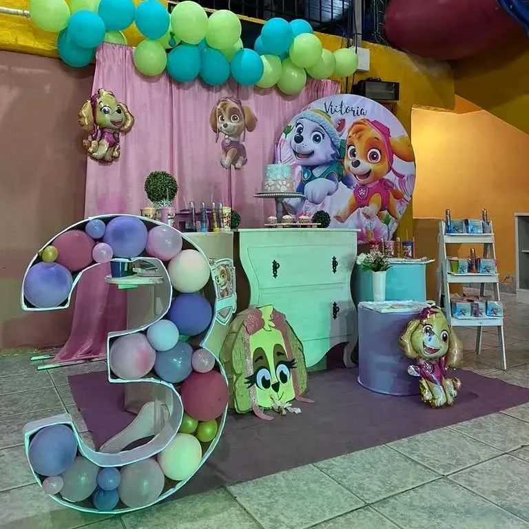 Fiesta temática de Paw Patrol con globos, pastel y decoraciones. Combinación de colores rosa, azul y verde.
