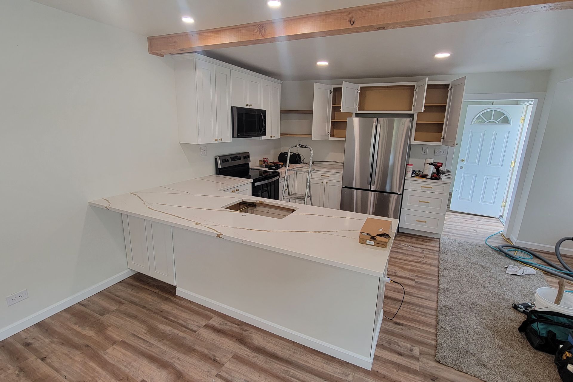 A kitchen with white cabinets and stainless steel appliances is being remodeled.