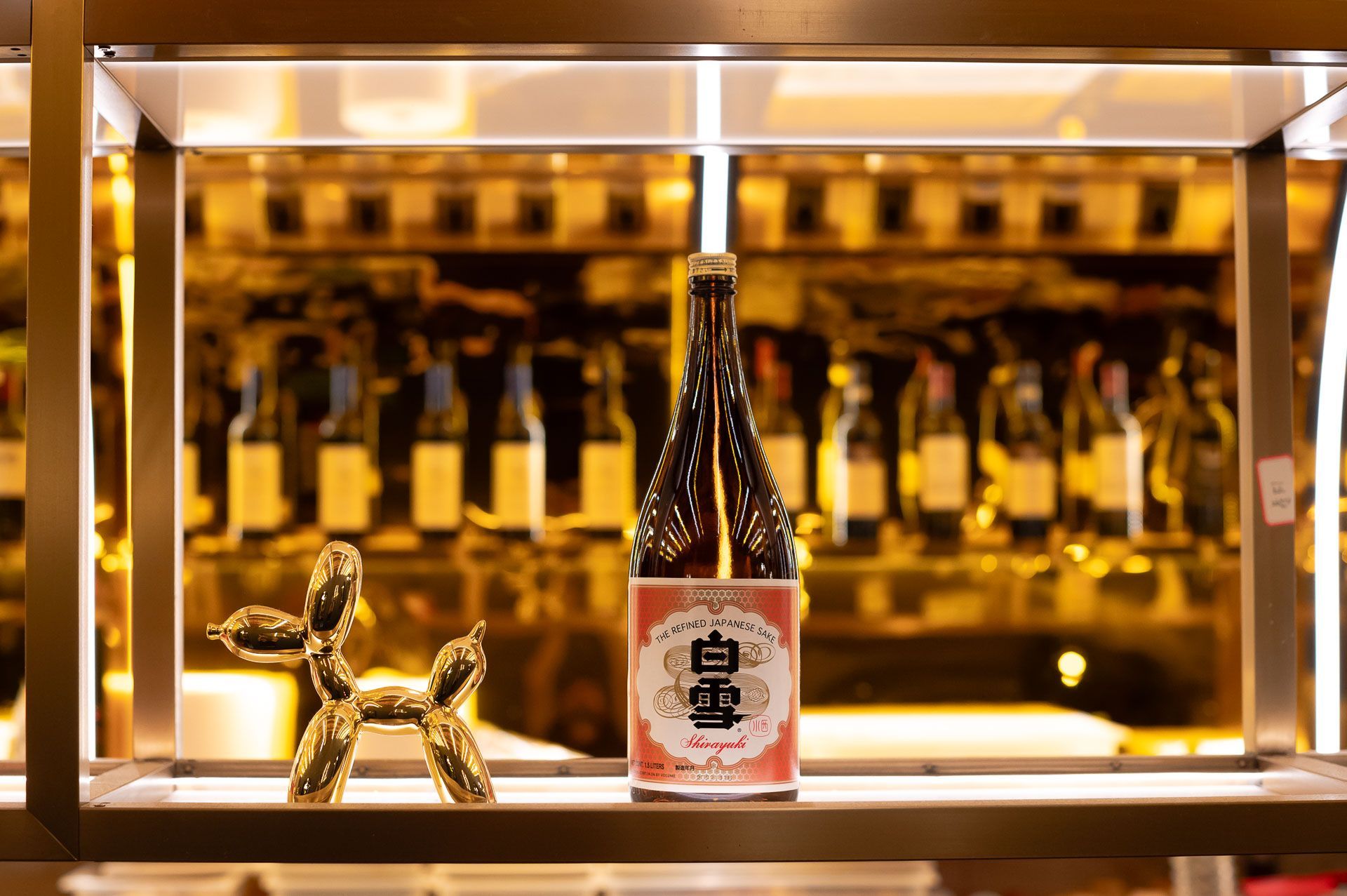 Una bottiglia di vino è appoggiata su uno scaffale davanti al bancone del bar.