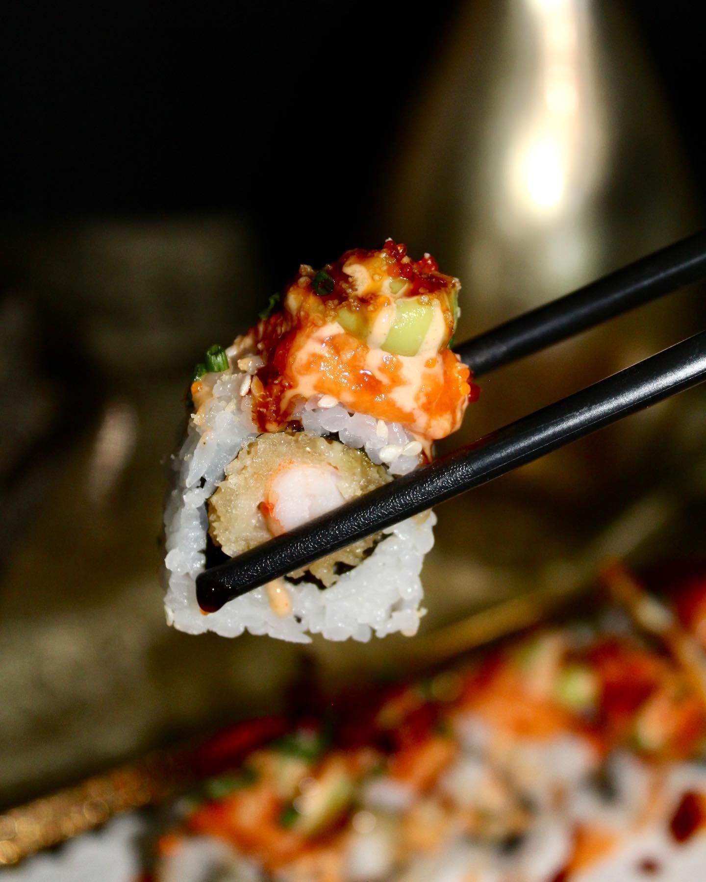 Un primo piano di bacchette che tengono un pezzo di sushi