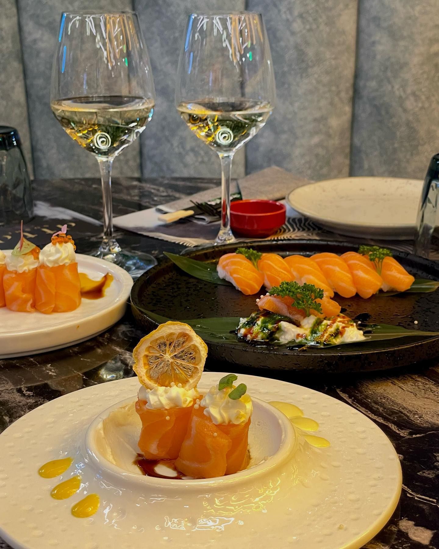 Un tavolo sormontato da piatti di cibo e bicchieri di vino.