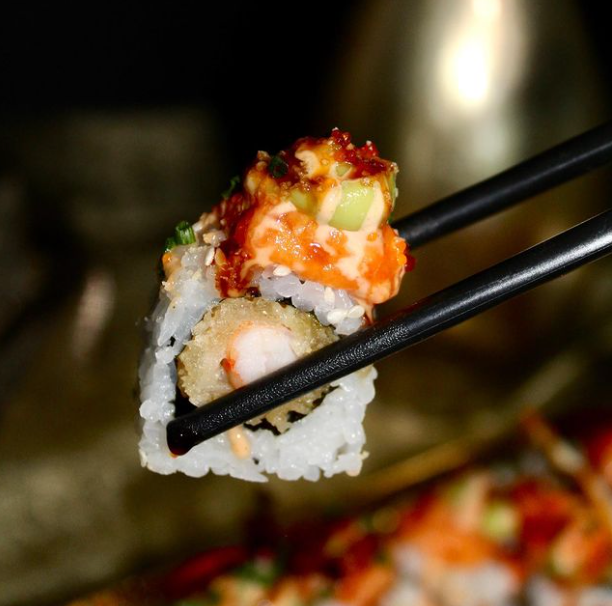 Un primo piano di bacchette che tengono un pezzo di sushi