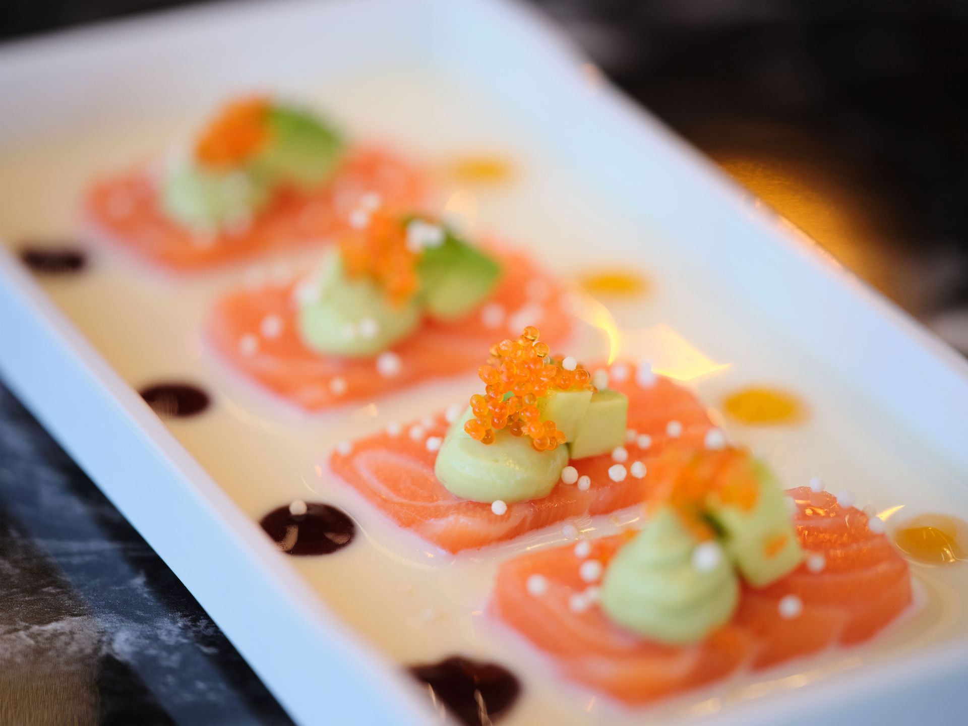Un primo piano di un piatto di cibo con salmone e avocado su un tavolo.