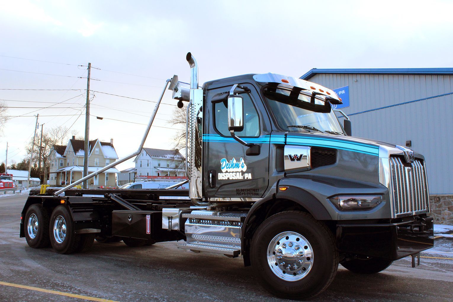 Deihm's Disposal of PA's dump truck is parked on the side of the road in front of a building.