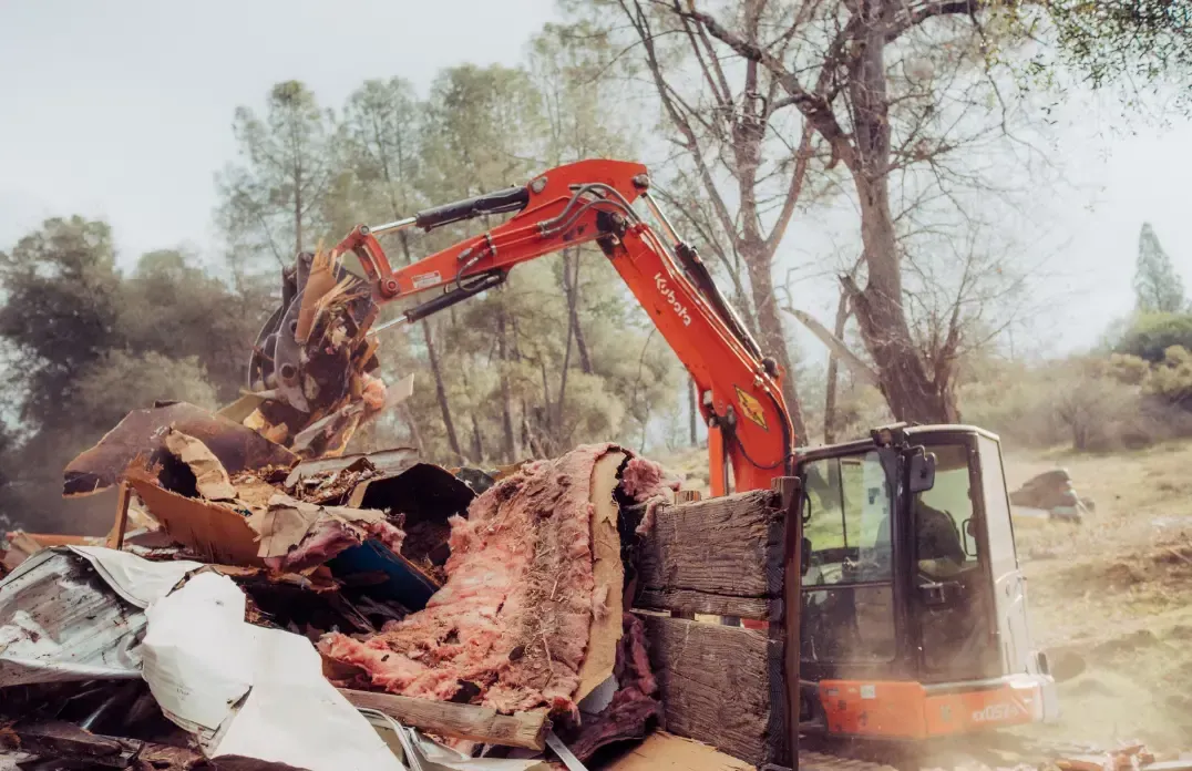 A bulldozer is demolishing a building in a field.