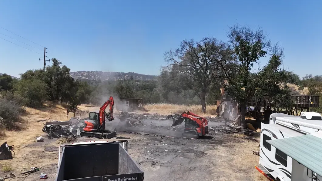 A large excavator is moving dirt in a field next to a rv.