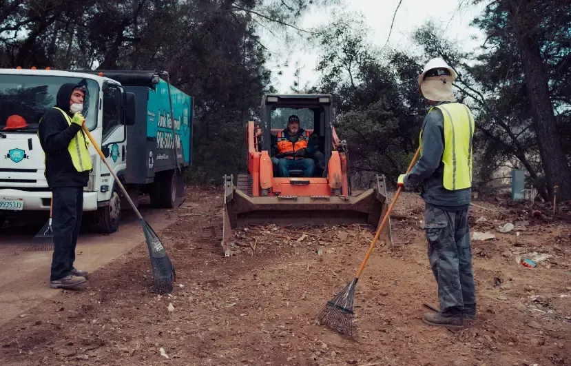 A group of men are standing in front of a bulldozer and a dump truck.