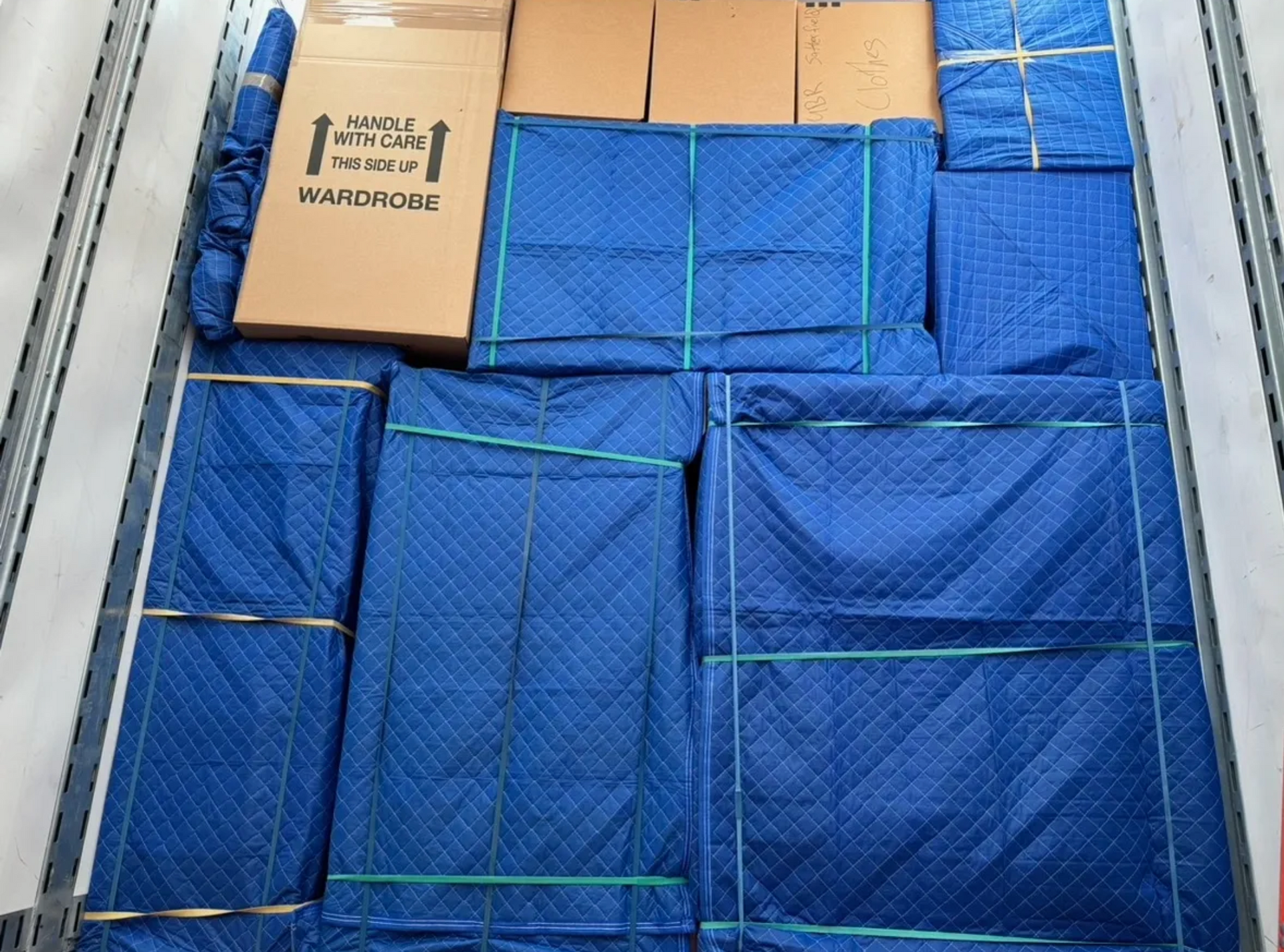 A bunch of boxes are wrapped in blue blankets in a truck.