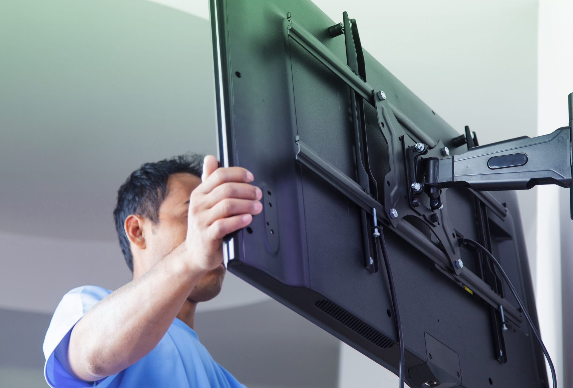 A man is installing a flat screen tv on a wall mount.