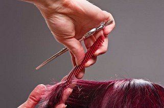Close-up of red hair being cut