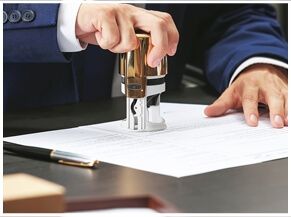Person stamping document with an office stamp.