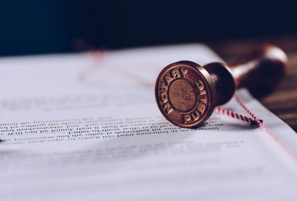 Stamp pressing down on a document, likely a legal agreement, on a wooden table.