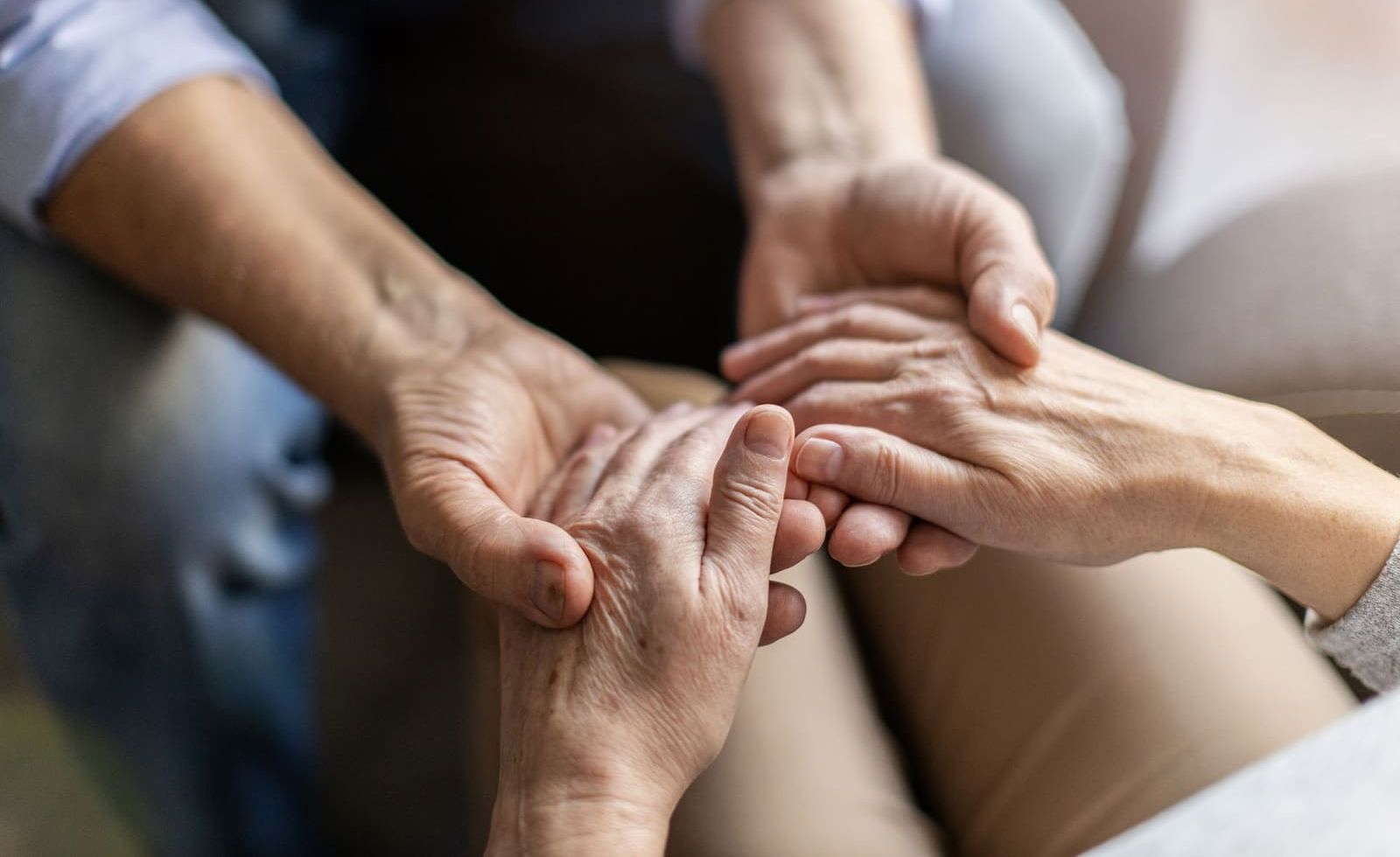 A man and woman are holding hands while sitting on a couch.