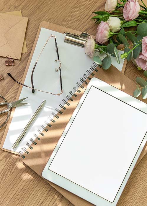 A man is standing next to a woman sitting on a couch looking at a laptop.