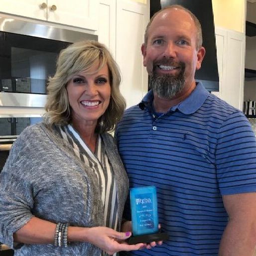 A man and a woman are posing for a picture in a kitchen.