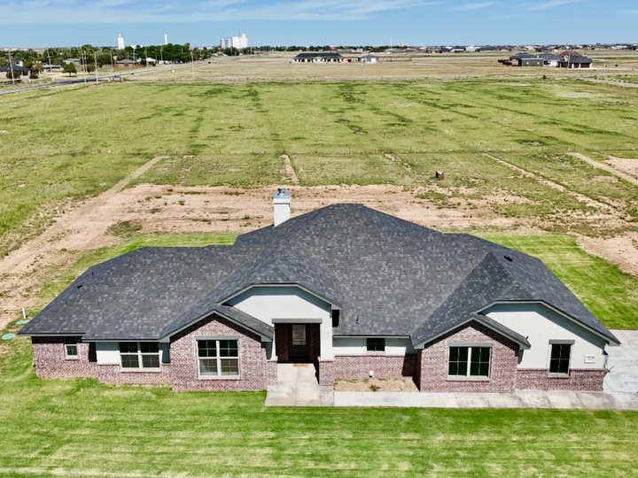 An aerial view of a house in the middle of a grassy field.