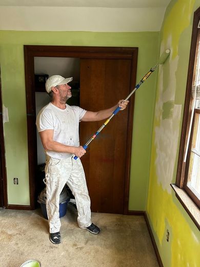 A man is painting a wall with a paint roller.