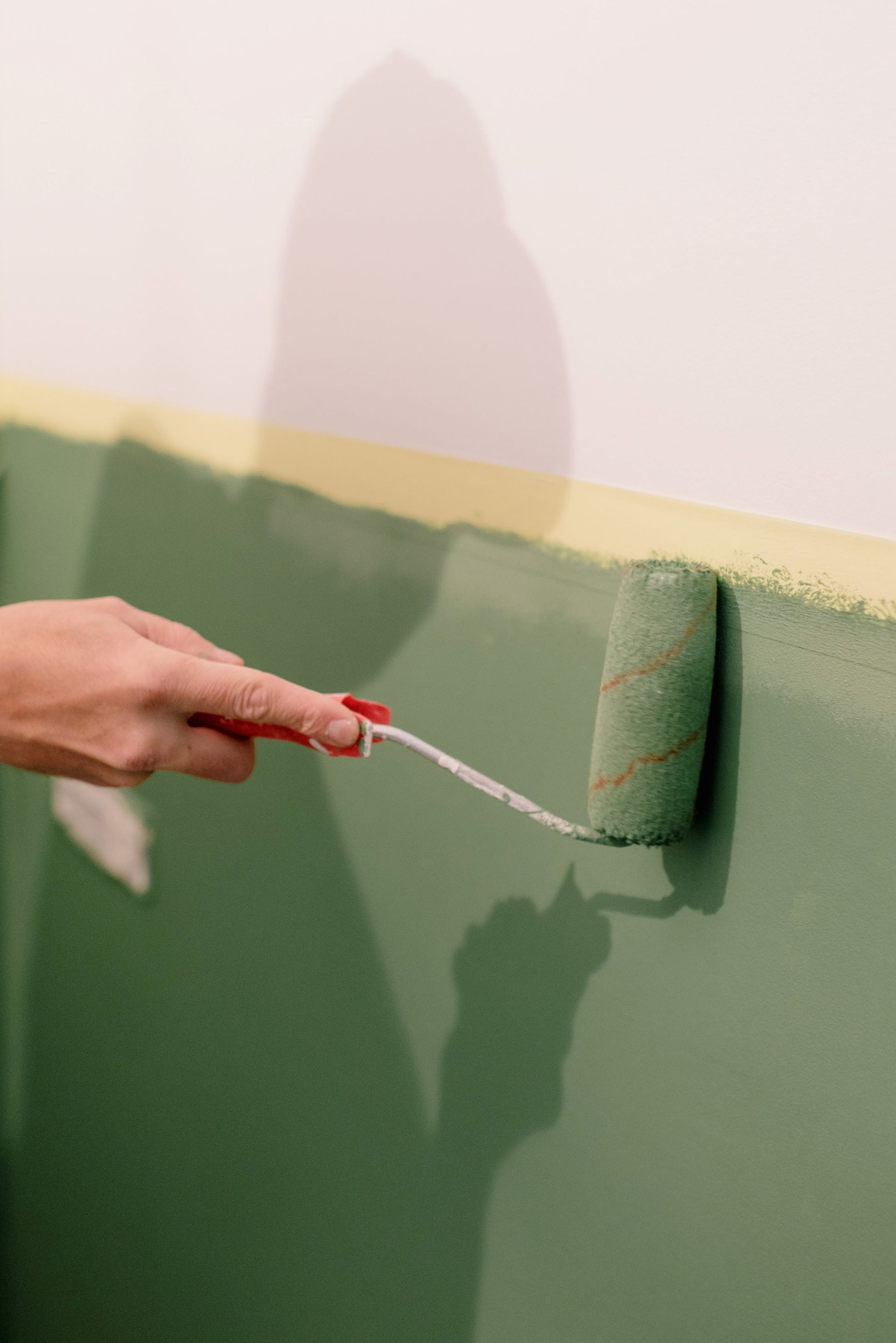 A person is painting a wall with a paint roller.