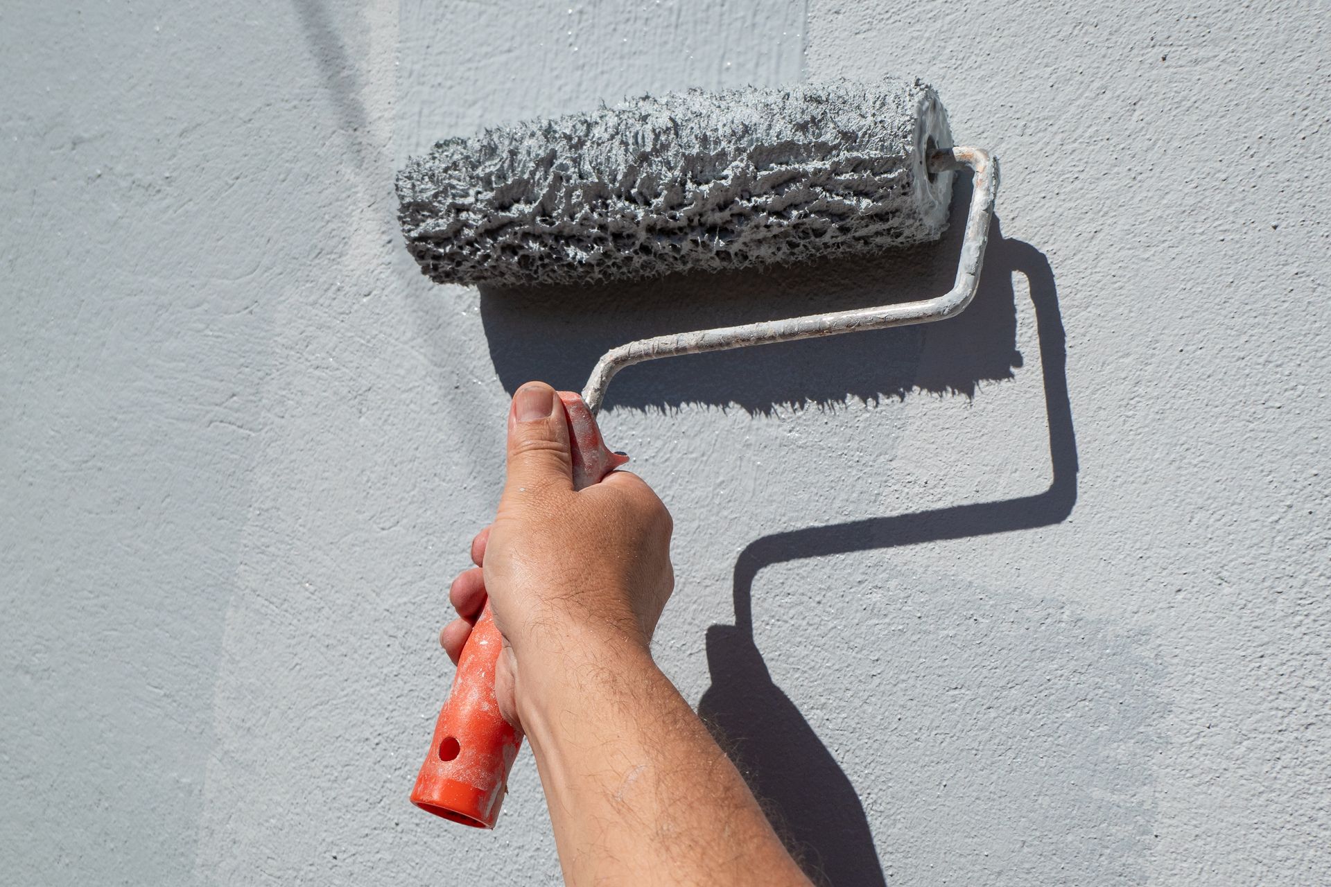 A person is painting a wall with a paint roller.