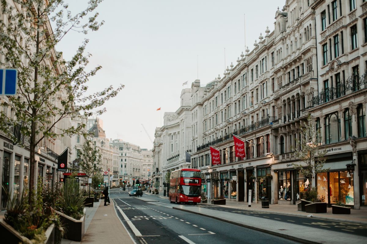 A red double decker bus is driving down a city street.