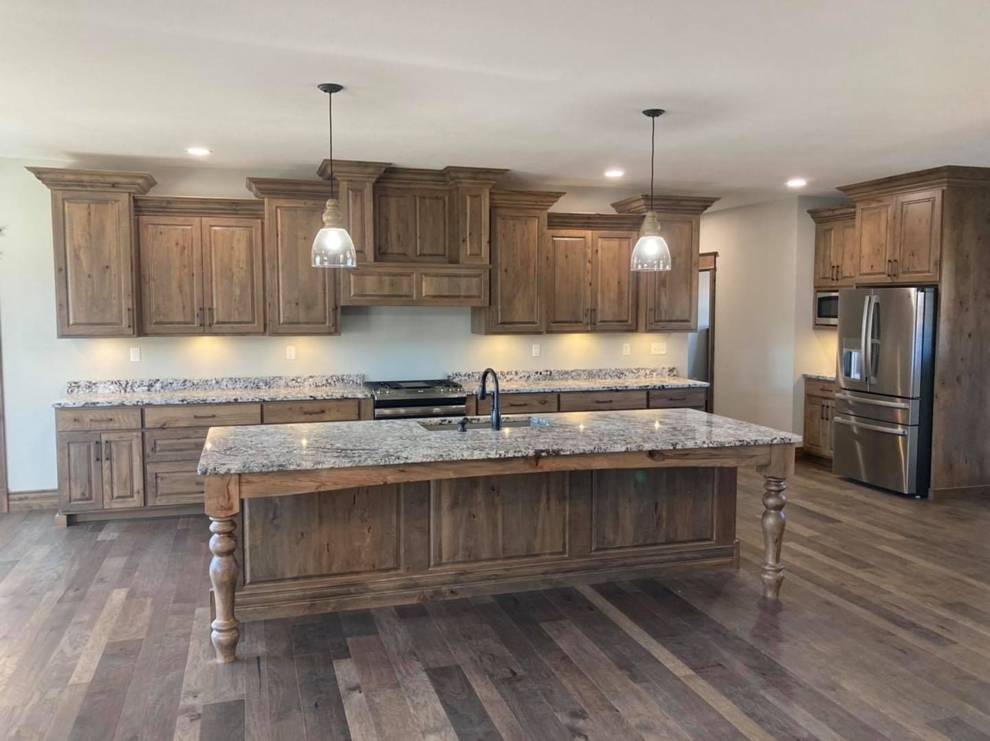 A kitchen with wooden cabinets , granite counter tops , stainless steel appliances and a large island.