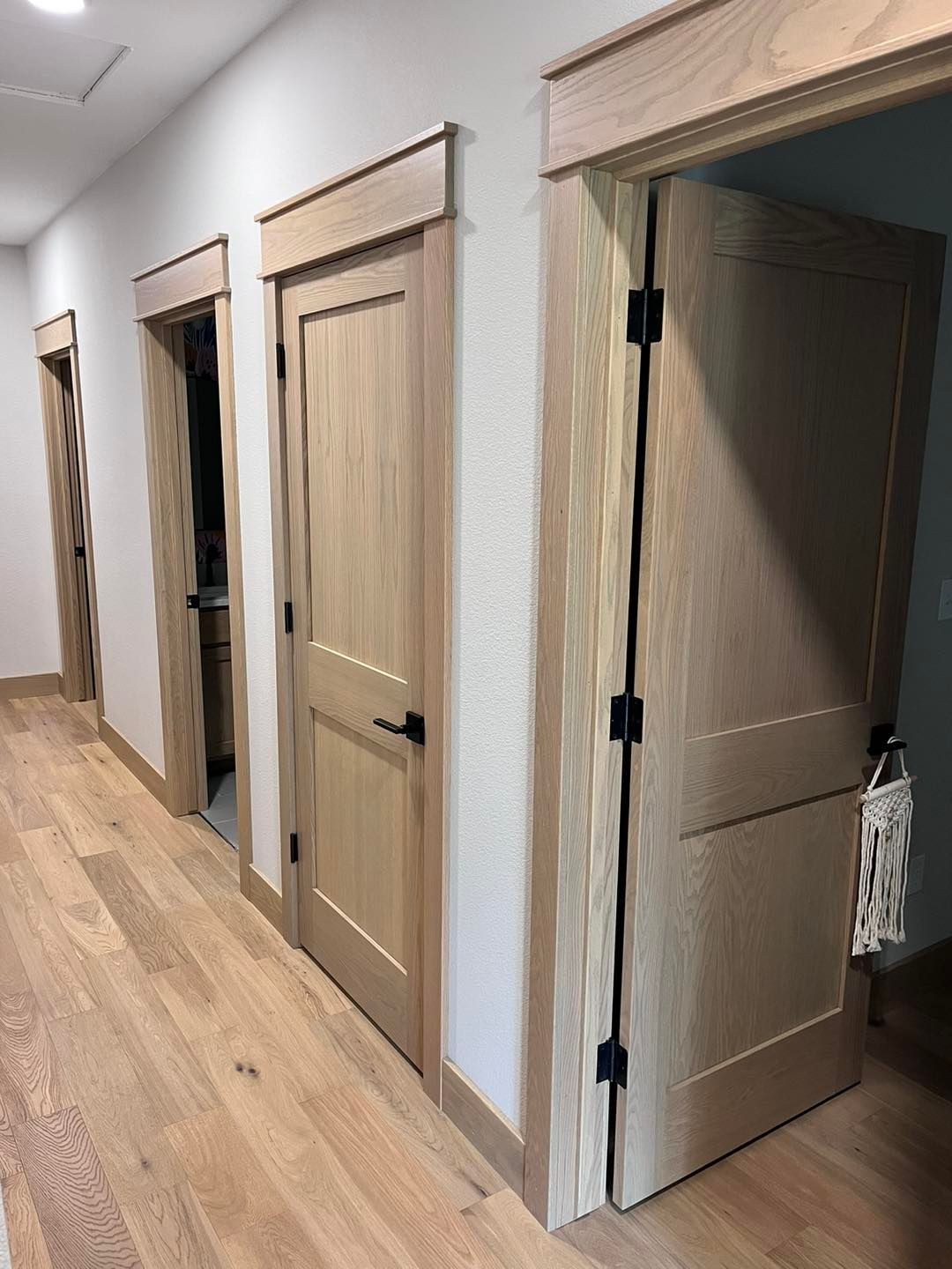 A hallway with wooden doors and hardwood floors in a house.