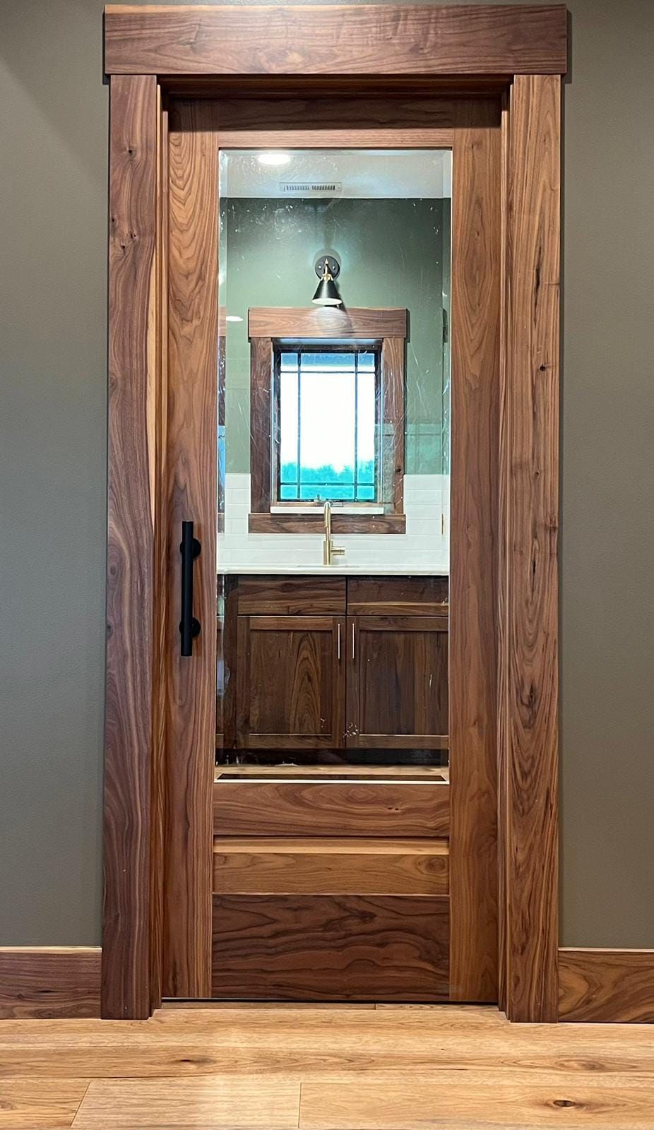 A wooden door leading to a bathroom with a sink and mirror.