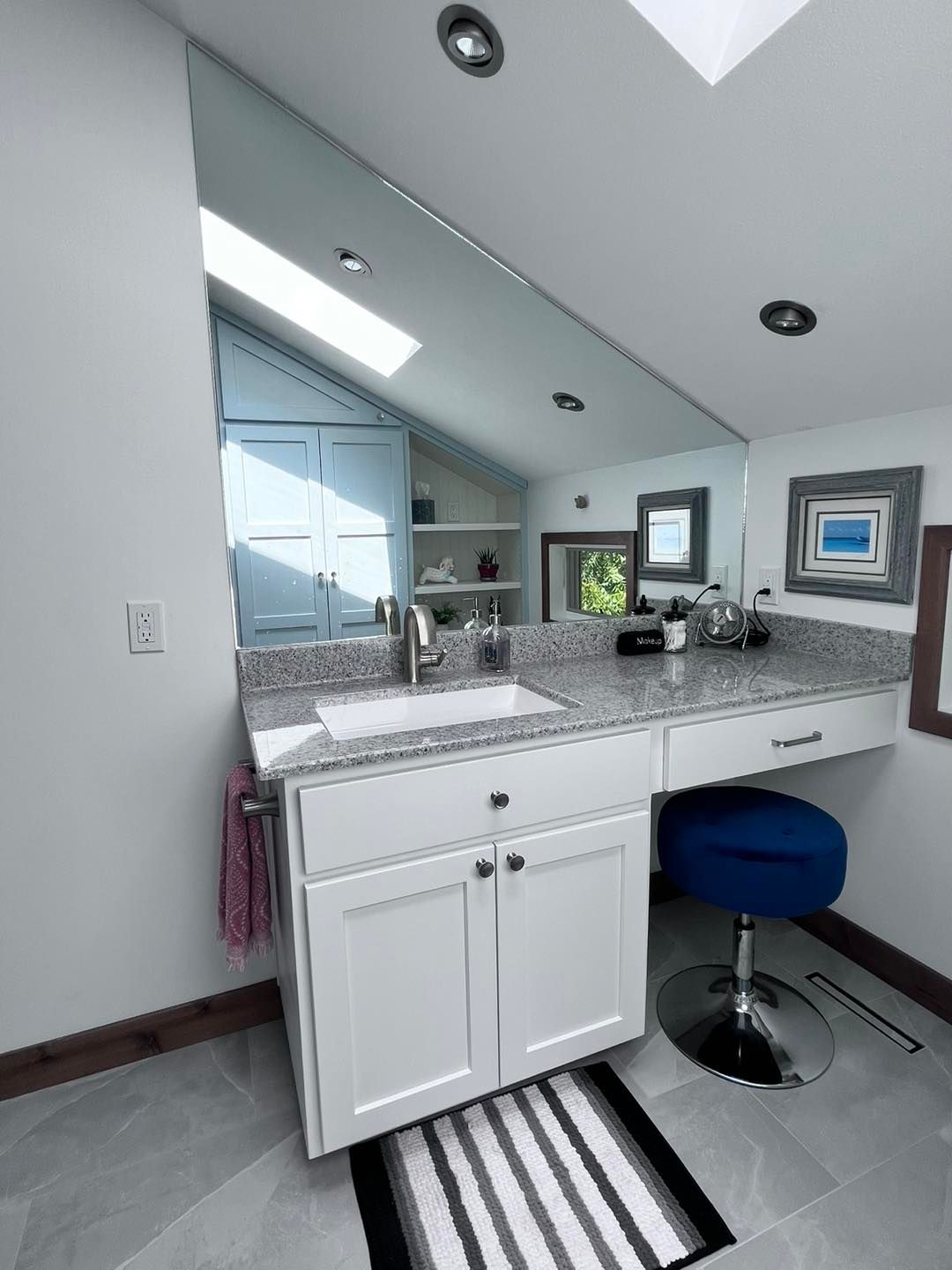 A bathroom with a sink , mirror and stool.