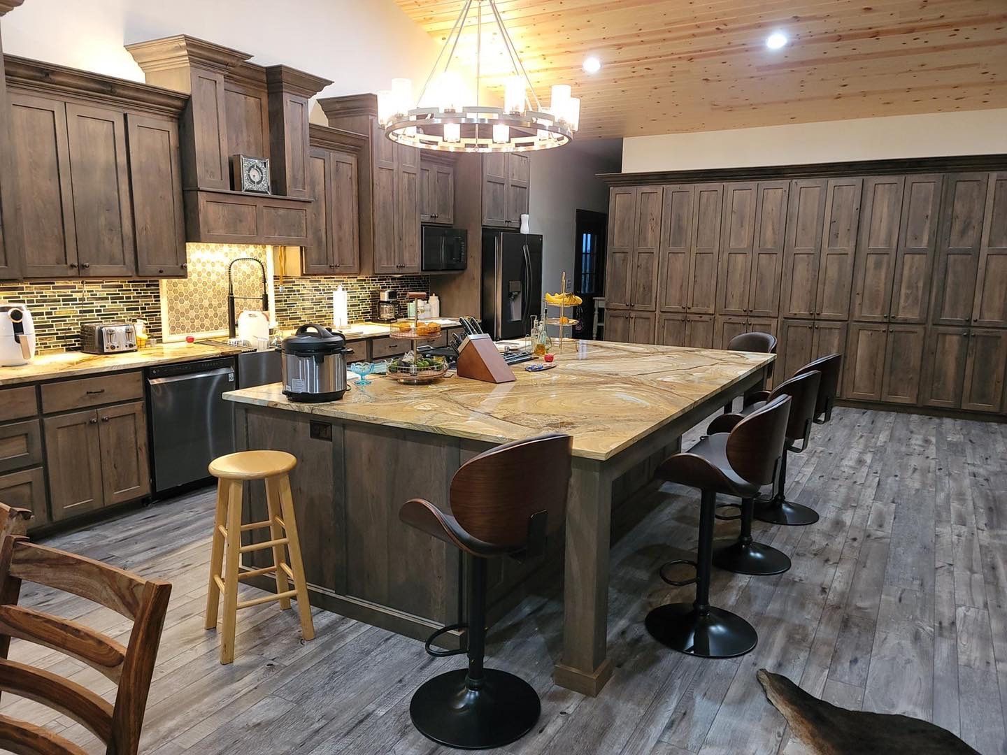 A kitchen with a large island , stools , and a chandelier.