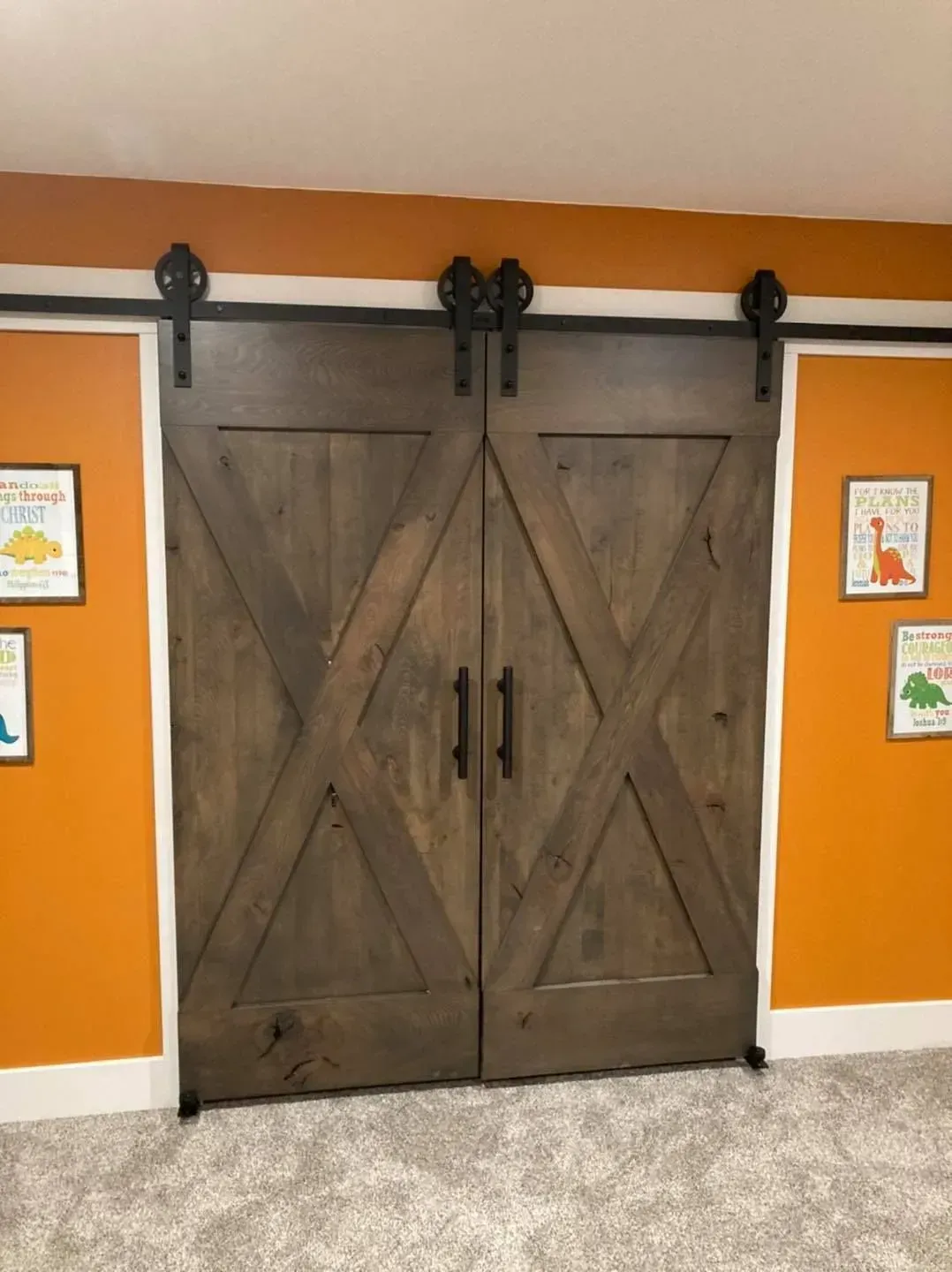 A pair of sliding barn doors in a room with orange walls.