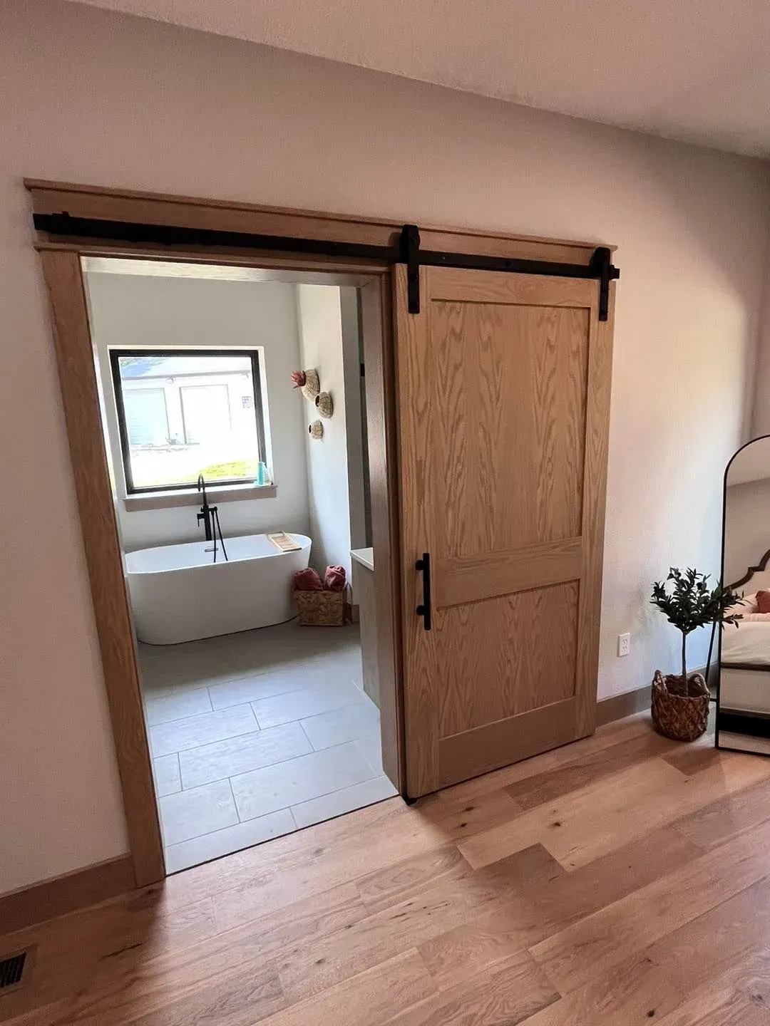 A bedroom with a sliding barn door leading to a bathroom.