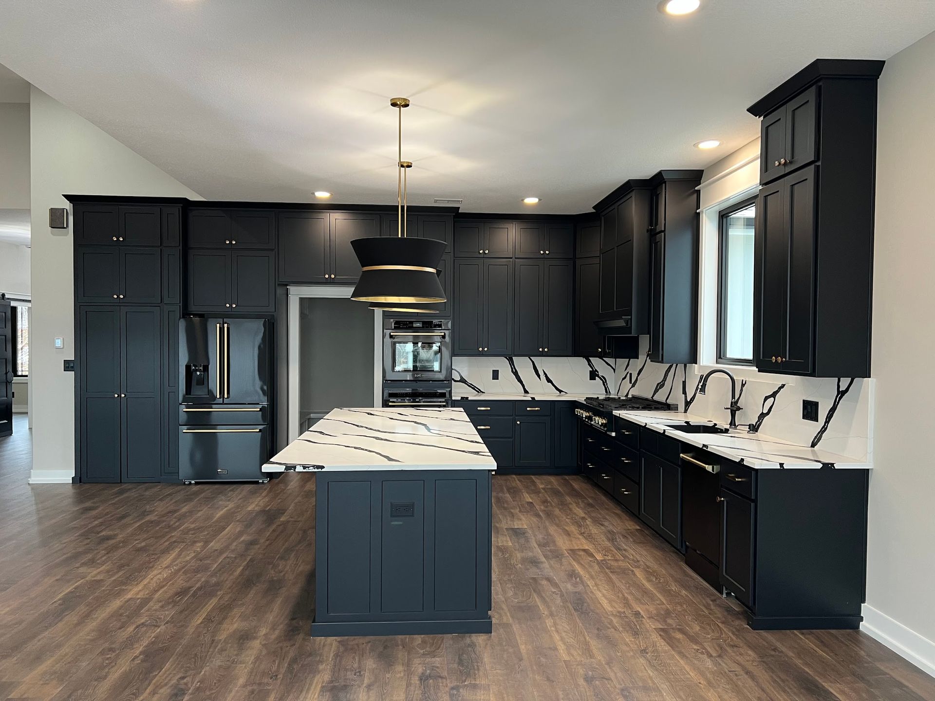 A kitchen with black cabinets and a large island in the middle.