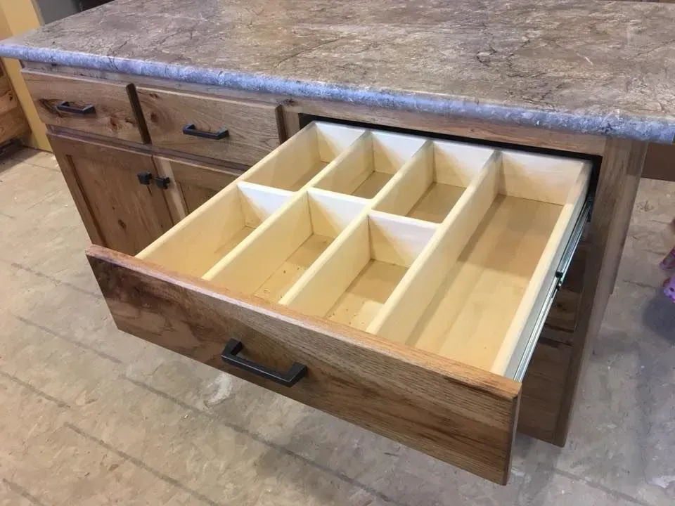 A wooden drawer with dividers in it is open on a counter.