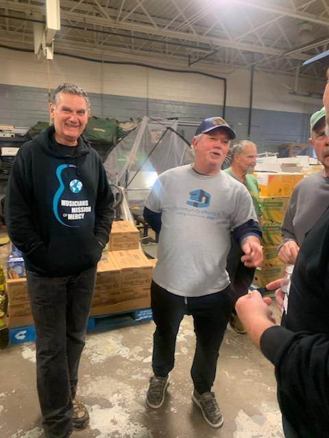 A group of men are standing in a warehouse talking to each other.